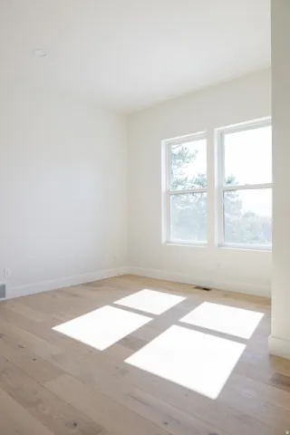 Bright room featuring two windows, wood-finish flooring, white baseboards, and recessed ceiling lighting