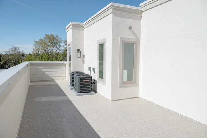 Rooftop patio featuring a textured light-colored surface, white stucco exterior, and modern rectangular windows with contrasting trim