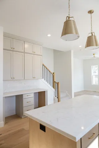 Kitchen island with a white stone countertop, integrated power outlet, and light wood-finish base