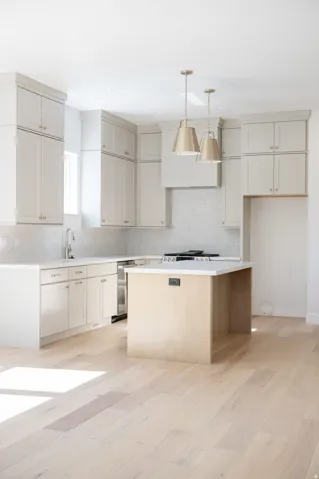 Bright kitchen featuring light-toned cabinetry, a central island with a light wood finish, and light wood-finish flooring