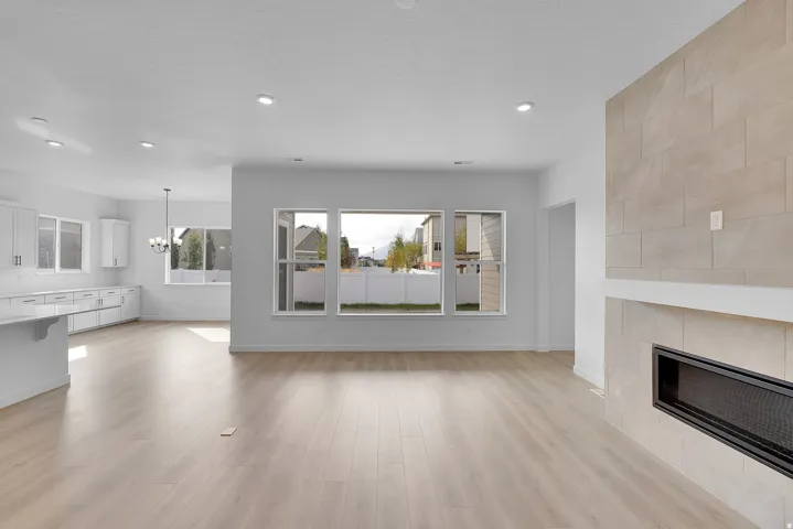 Open-concept living area with light wood-finish flooring, recessed lighting, and a modern fireplace with a tiled surround