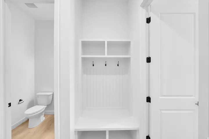 Built-in mudroom bench with upper cubbies, beadboard backing, and black hooks