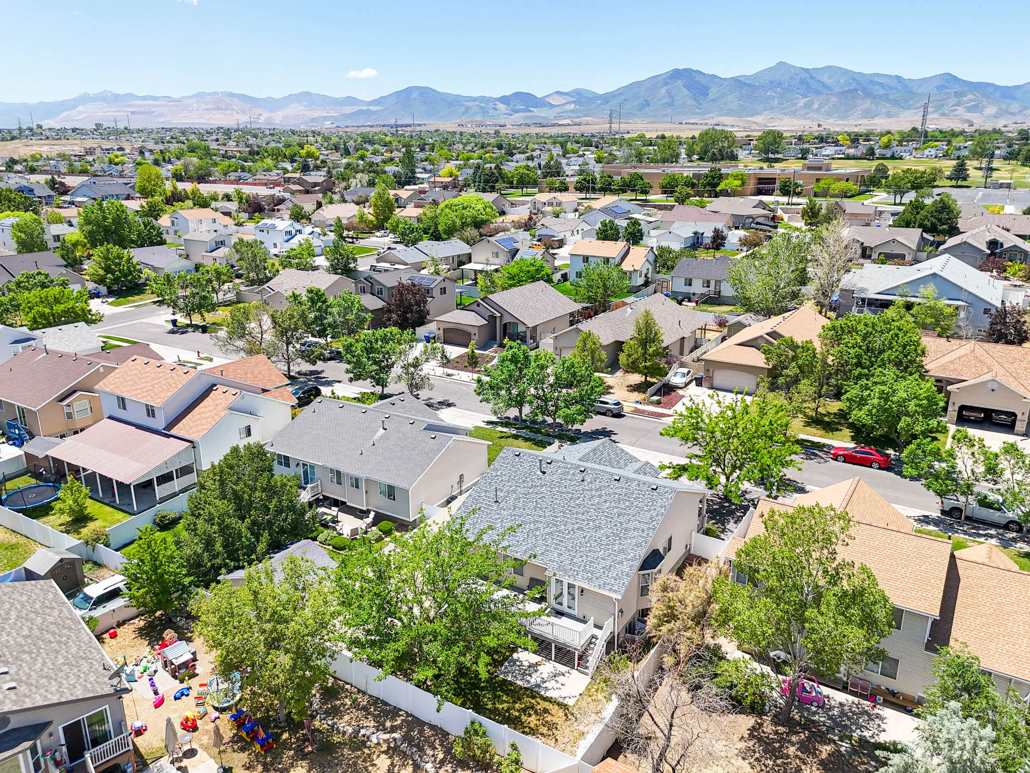 Residential neighborhood featuring an array of single-family homes with diverse architectural styles, mature trees, and mountainous terrain in the distance
