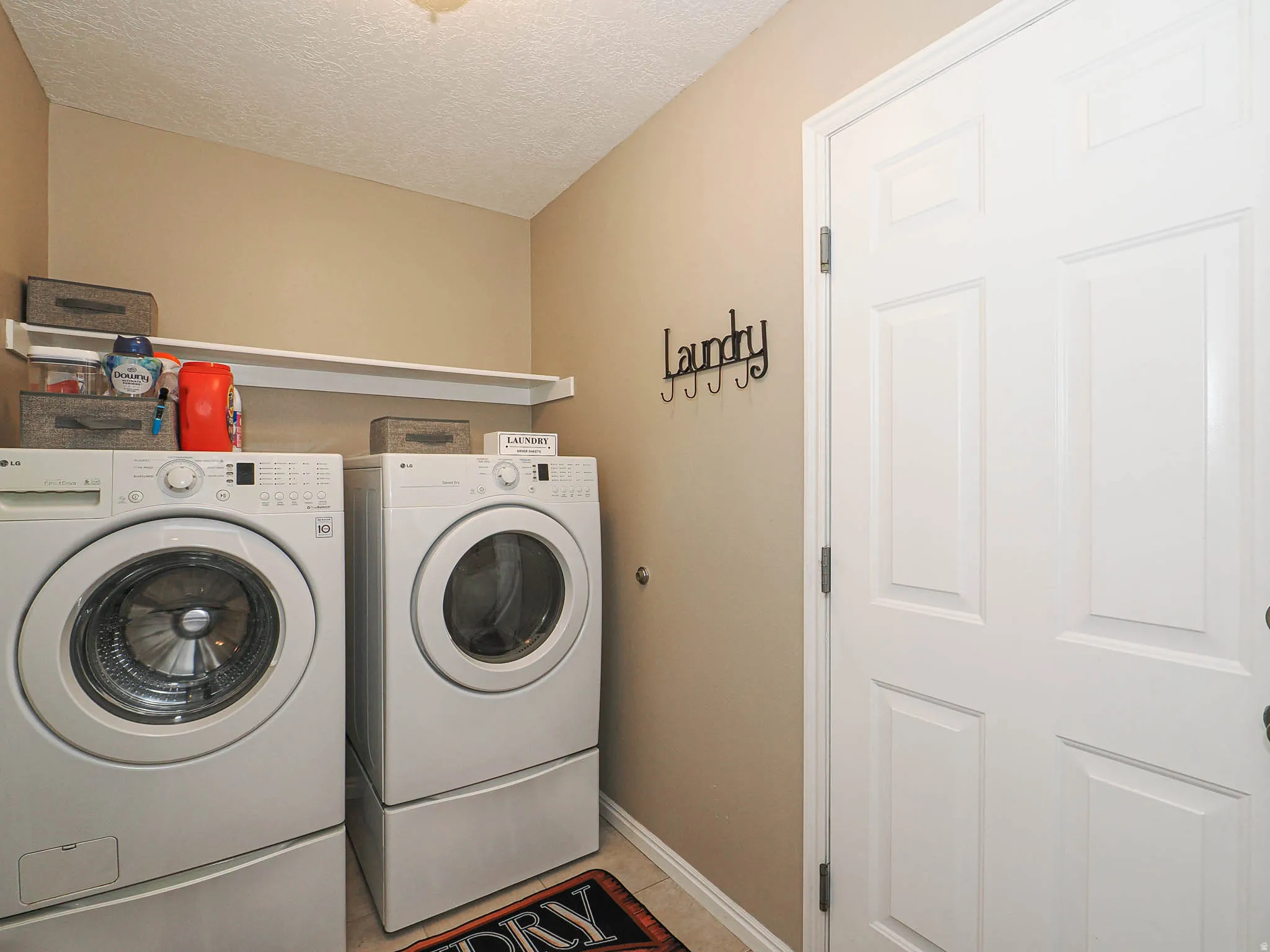 Dedicated laundry space featuring a white shelf and ceramic tile flooring