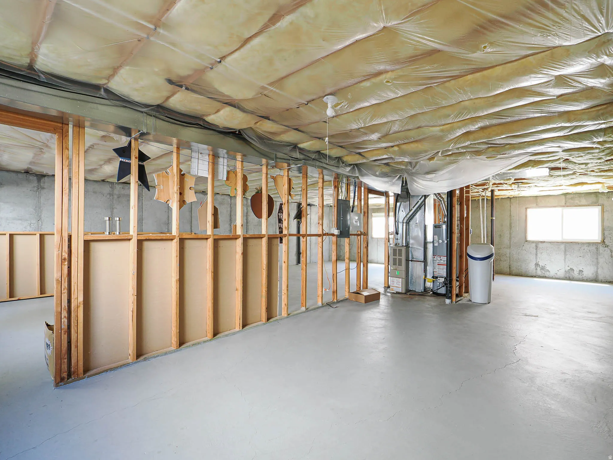 Expansive basement space featuring exposed wood framing, concrete walls, and painted concrete flooring