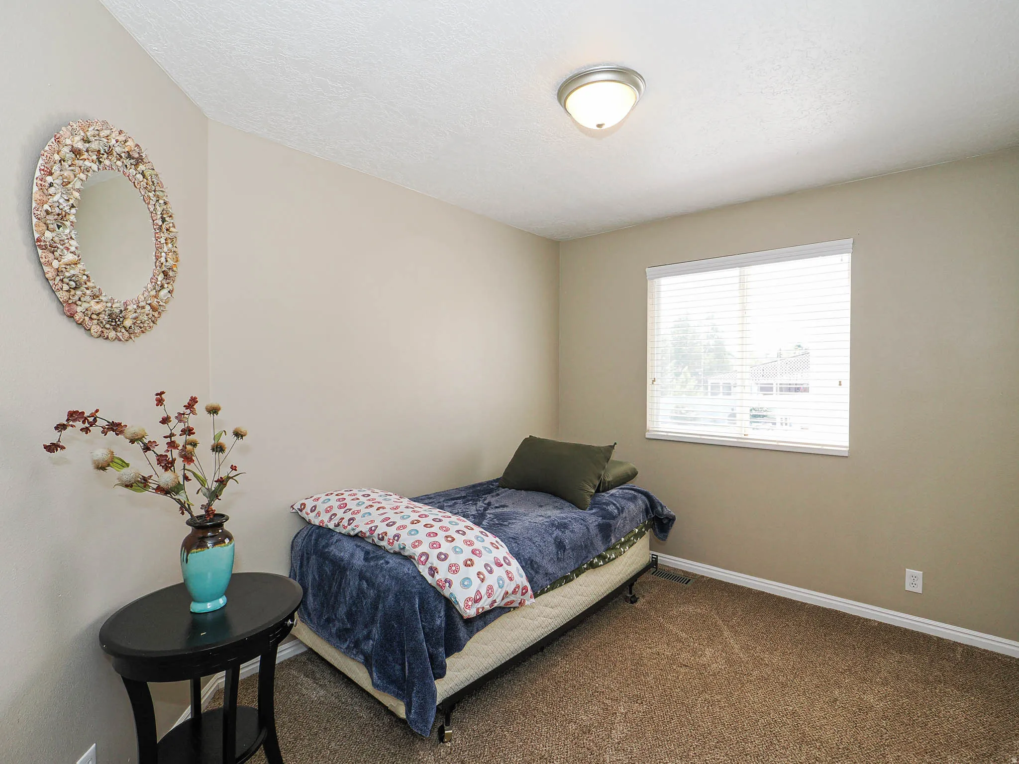 Bedroom featuring a single window with blinds, neutral wall paint, and textured carpeting
