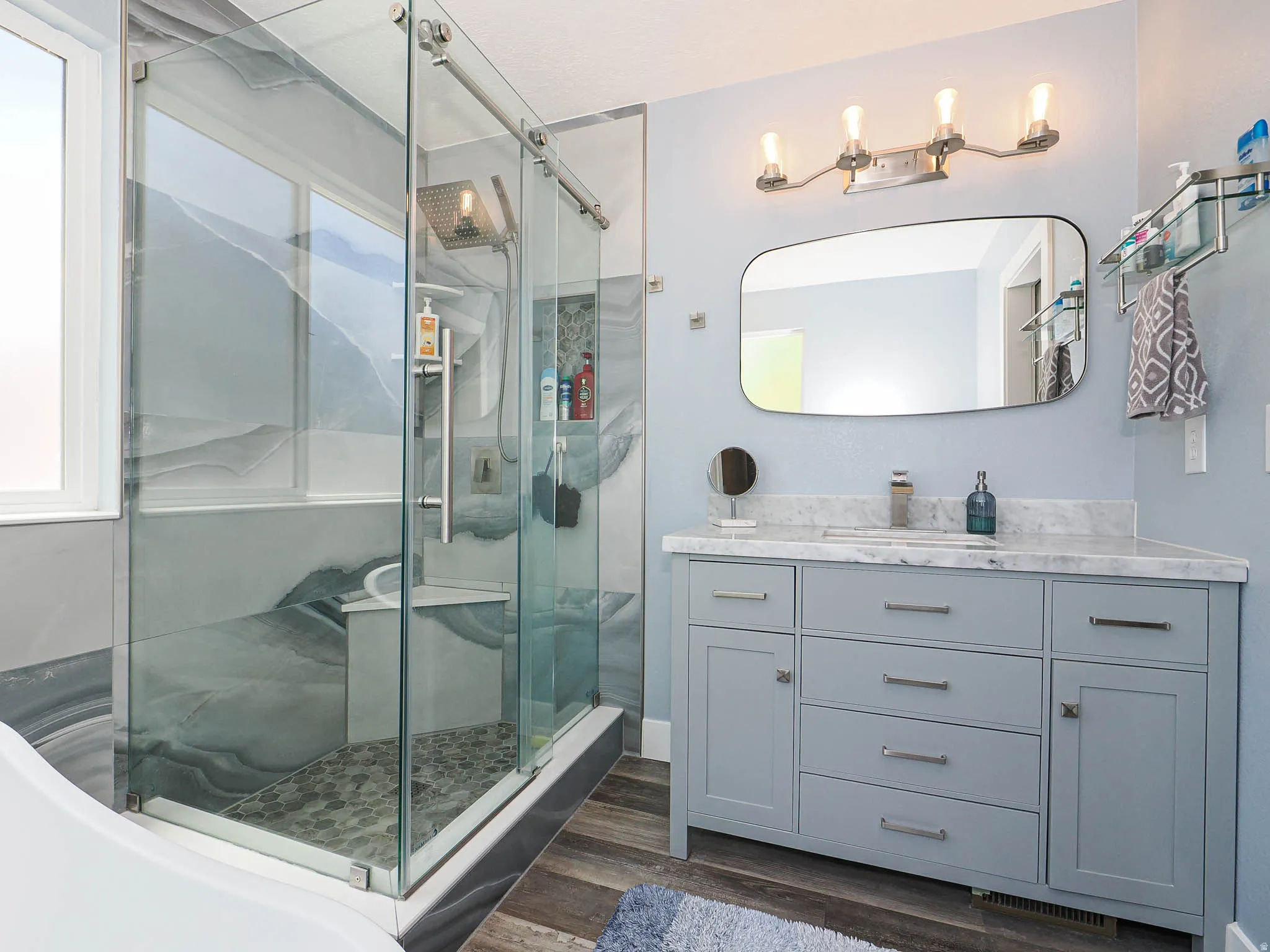 Modern bathroom featuring a glass-enclosed shower with a built-in bench, pebble-tile floor, and rain showerhead