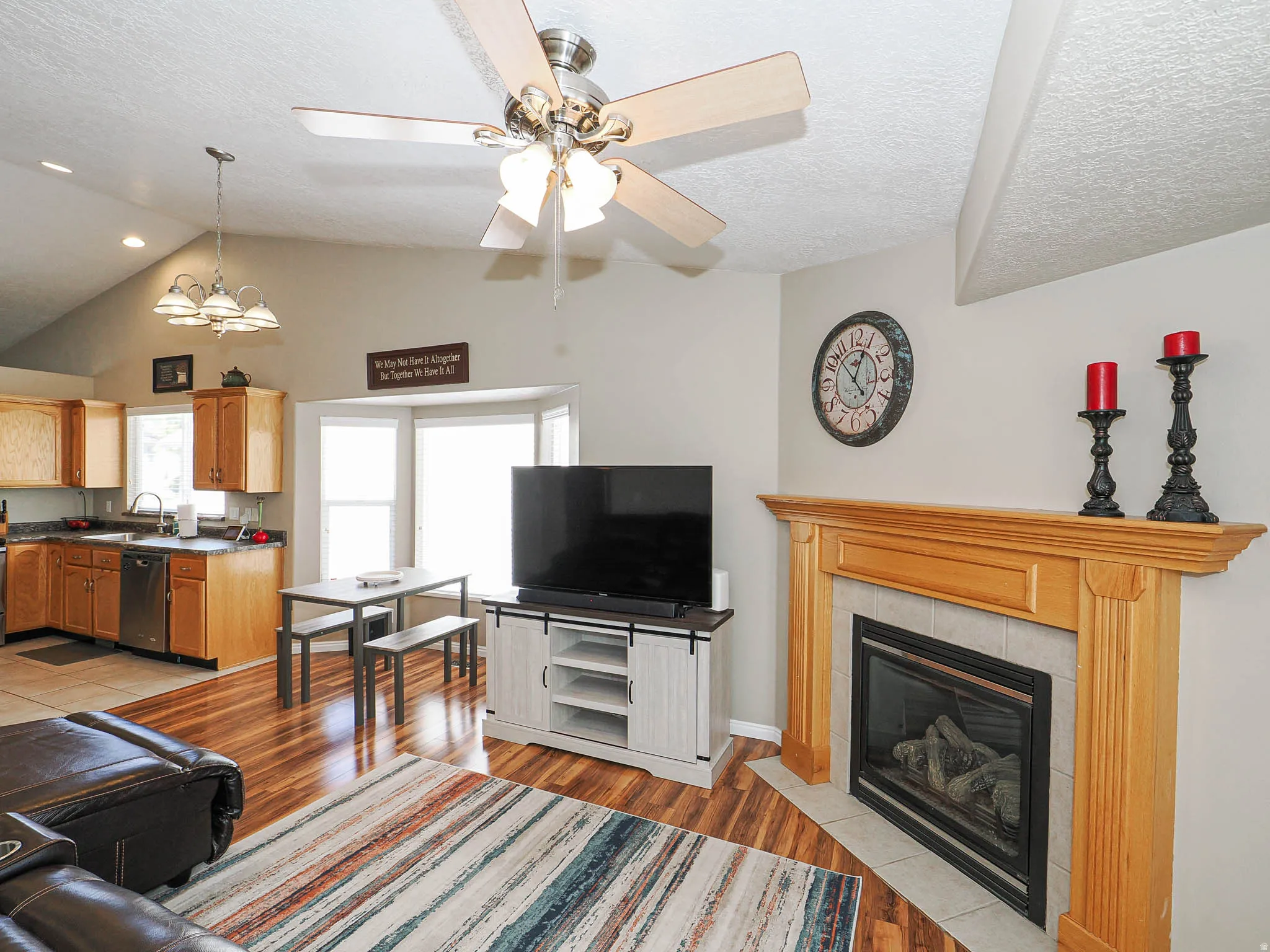 Open-concept living space featuring wood-finish flooring, a vaulted ceiling, and a ceiling fan