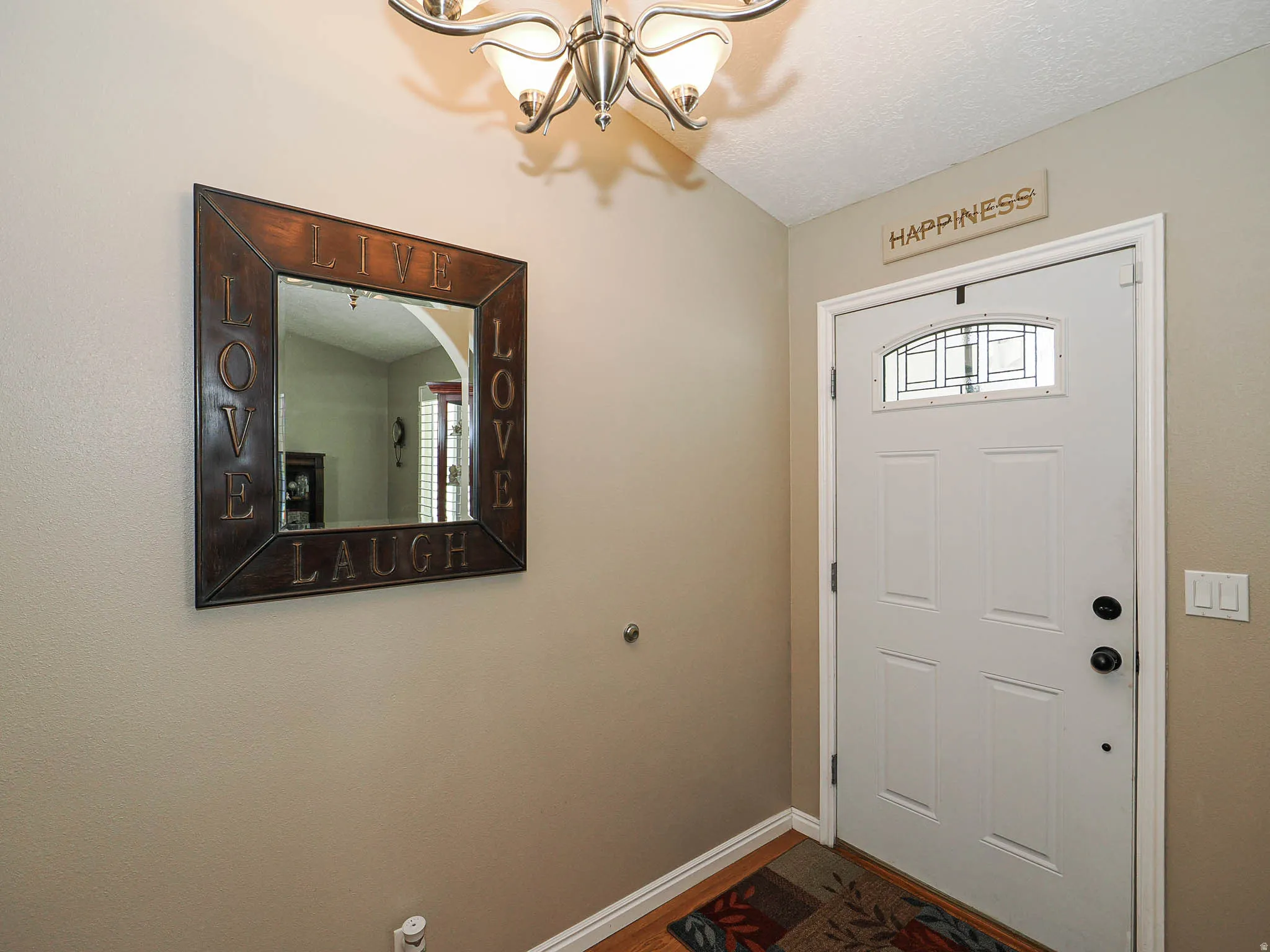 Entryway featuring a white paneled door with an arched decorative glass insert and an overhead chandelier with frosted glass shades