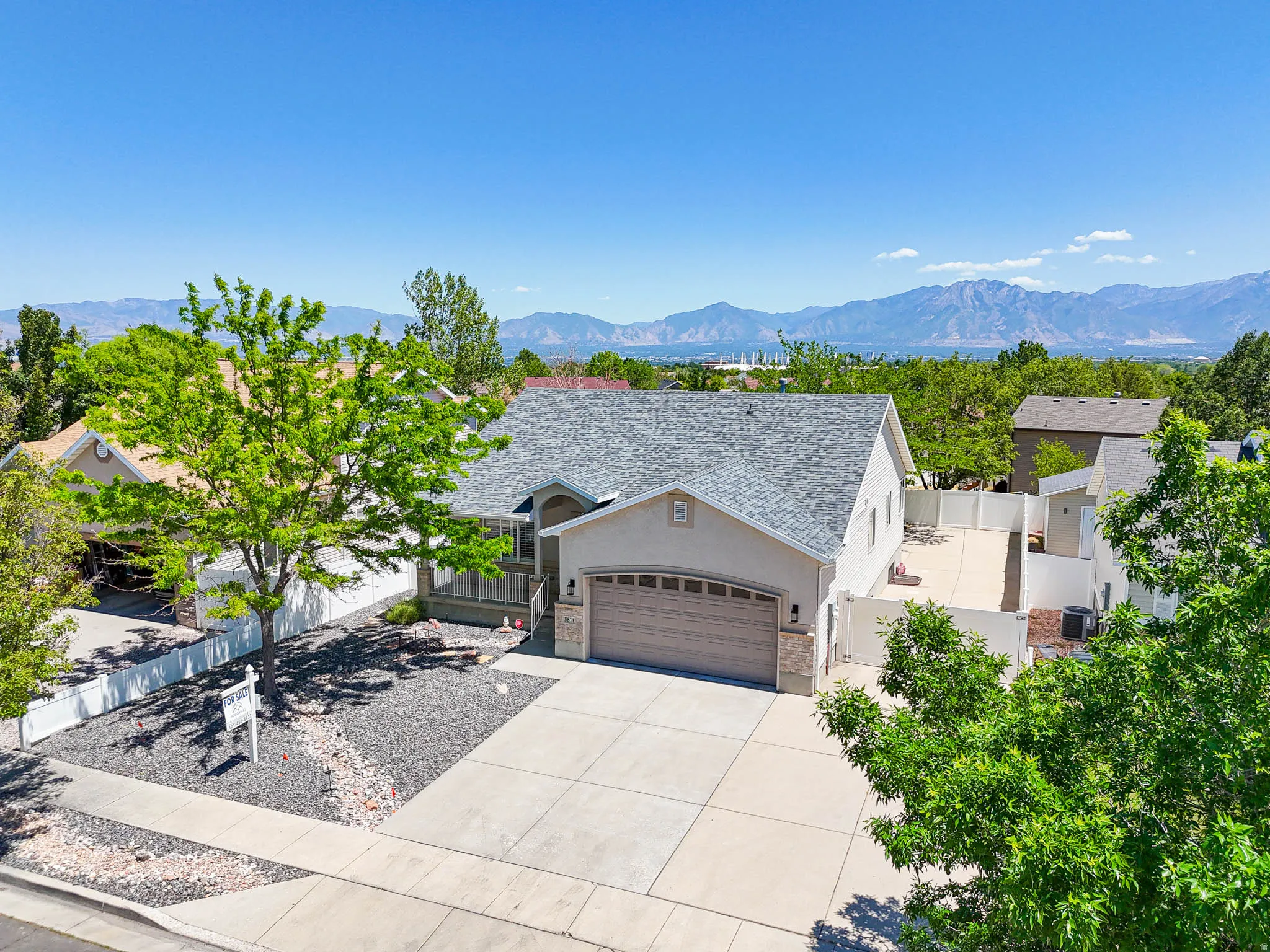 Single-family residence featuring a two-car garage, concrete driveway, and a white vinyl fence