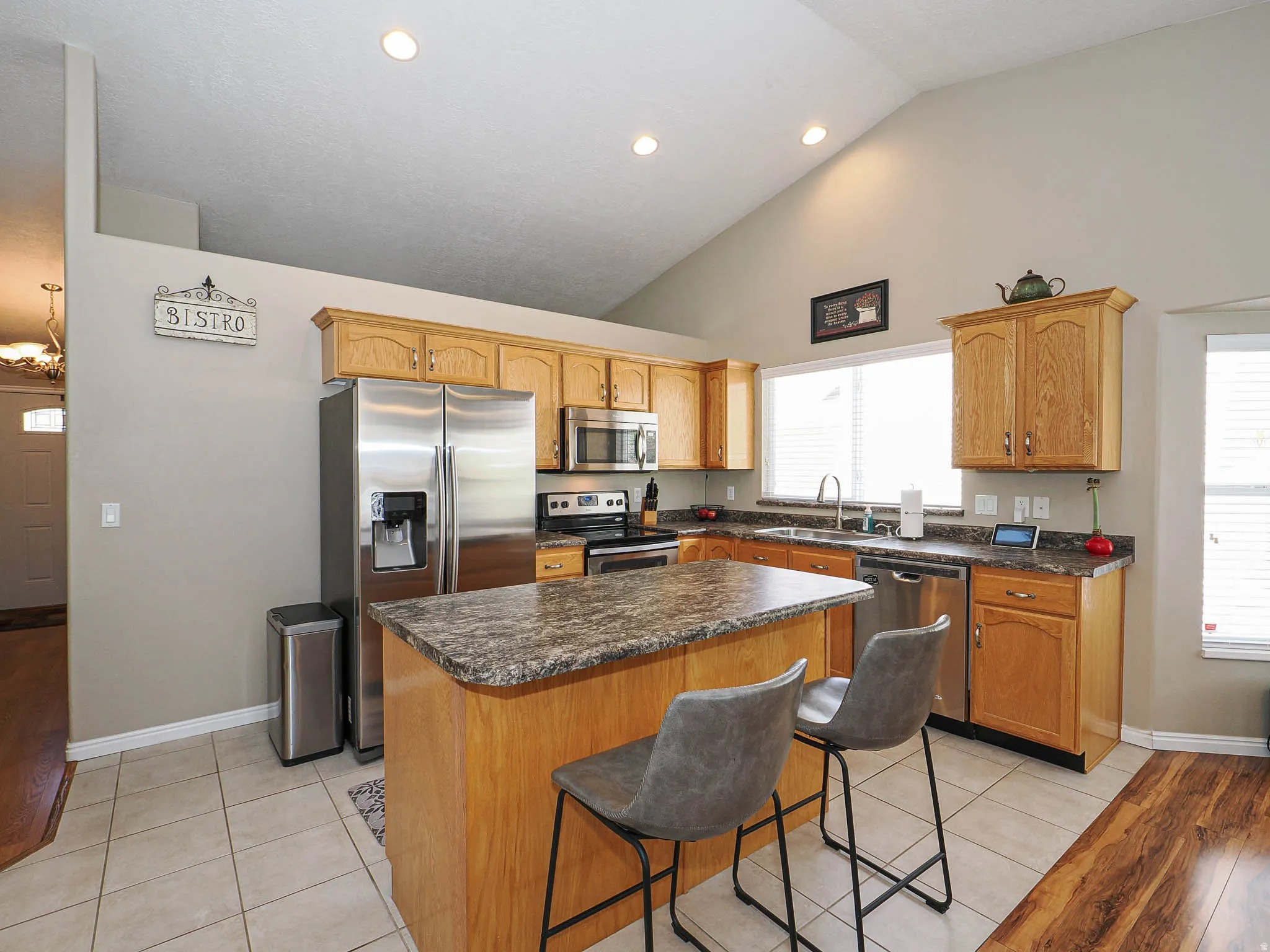 Kitchen featuring a vaulted ceiling with recessed lighting, an island with countertop seating, stainless steel appliances, and wood-finish cabinetry