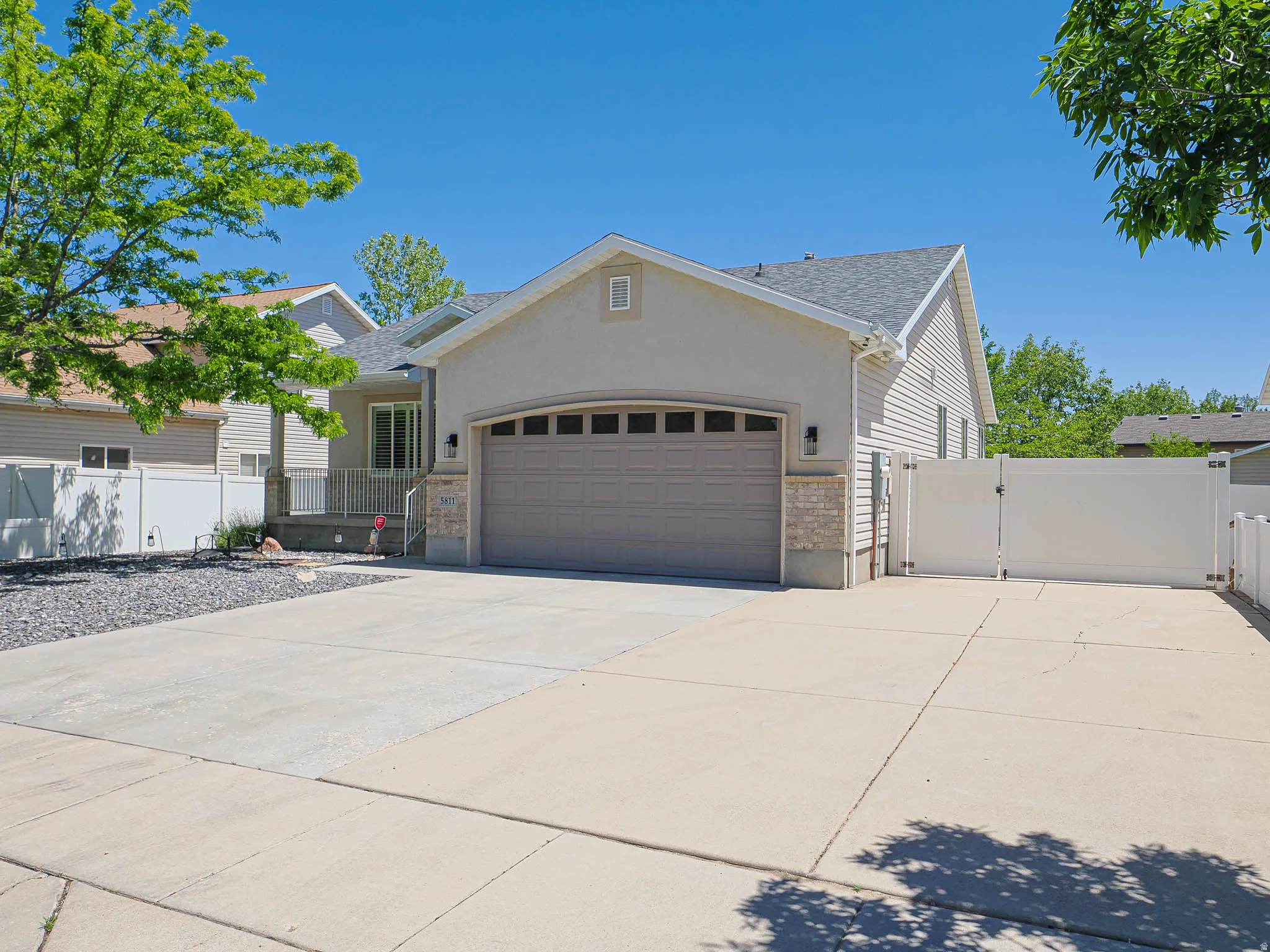 Exterior featuring a two-car garage, concrete driveway, stone accents, and a front porch with a railing
