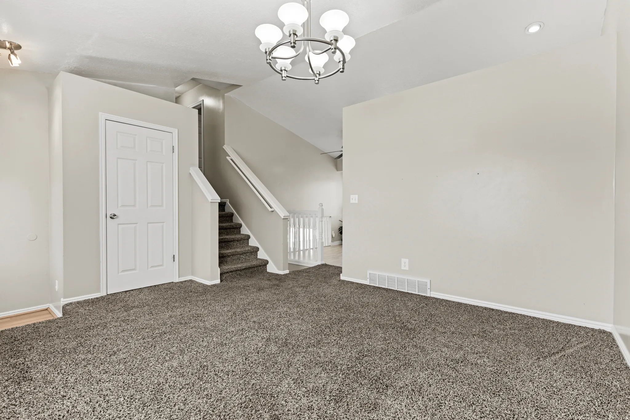 Spacious room with plush carpeting, neutral wall finishes, and a contemporary five-light chandelier