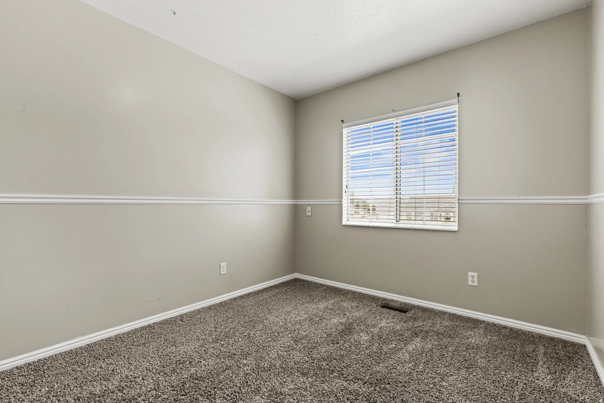Carpeted room with a single window featuring horizontal blinds