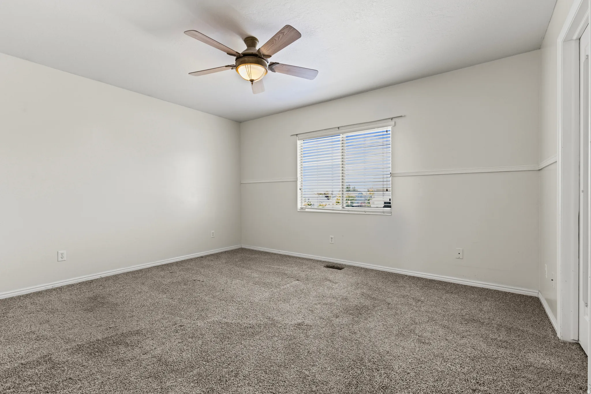 Spacious room featuring neutral carpeting and light-colored walls