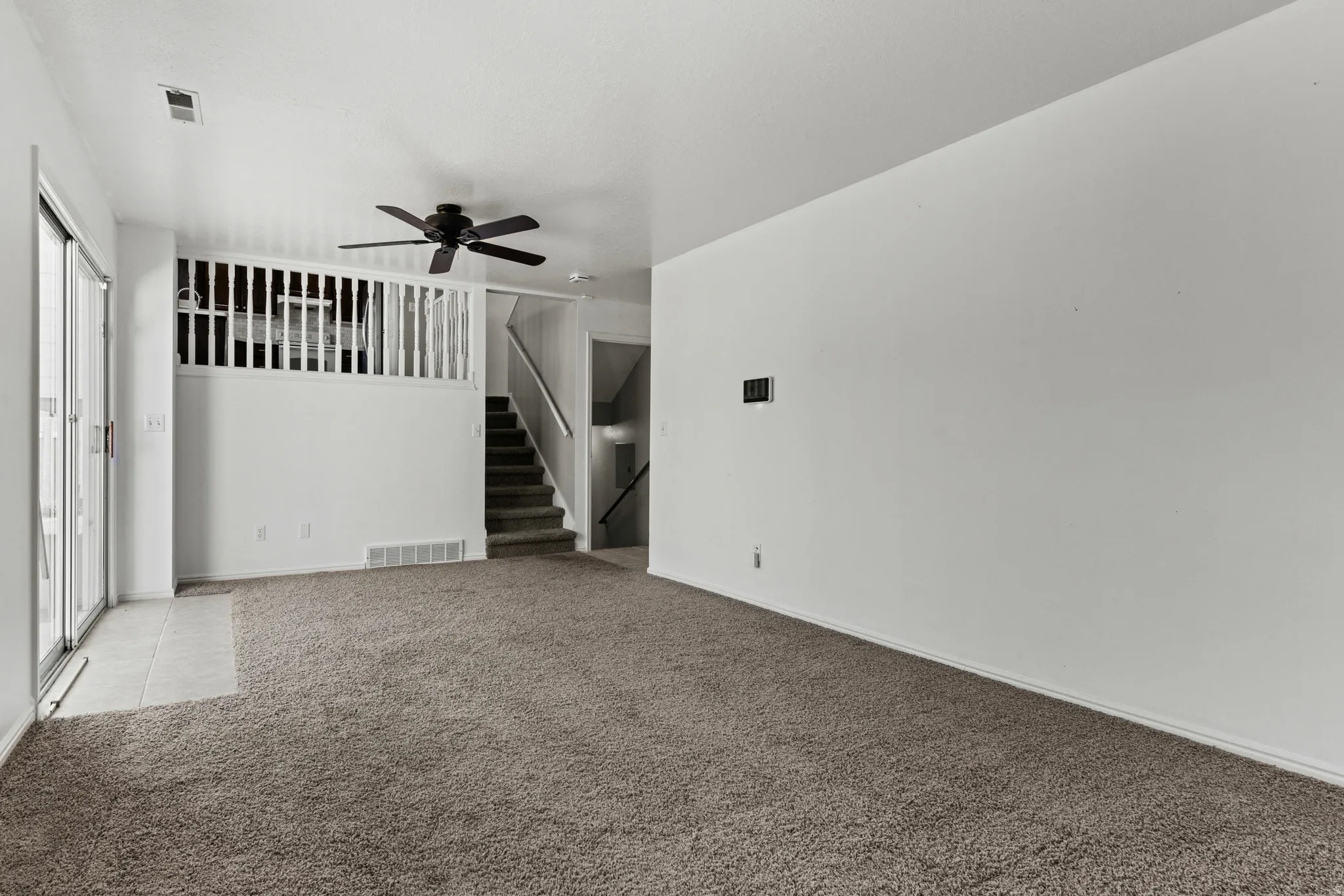 Spacious living area featuring neutral carpeting and white wall finishes
