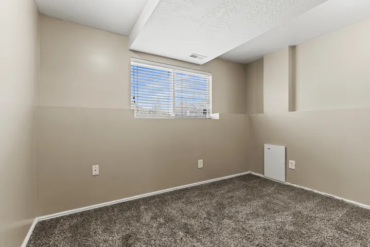 Room featuring a window with blinds, neutral two-tone paint, textured carpet flooring, and white trim