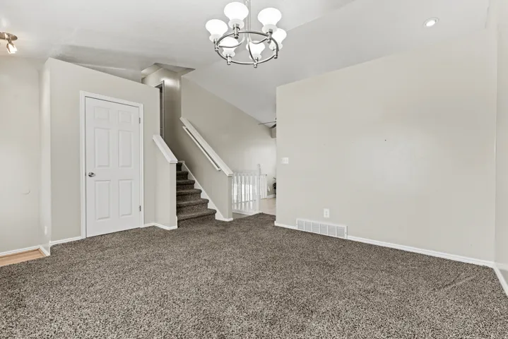 Spacious room with plush carpeting, neutral wall finishes, and a contemporary five-light chandelier
