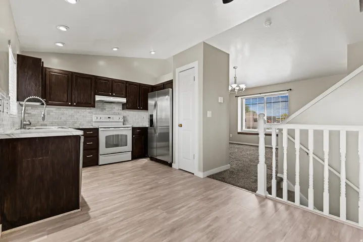 Kitchen featuring dark wood cabinetry, stainless steel refrigerator, white range, and a subway tile backsplash