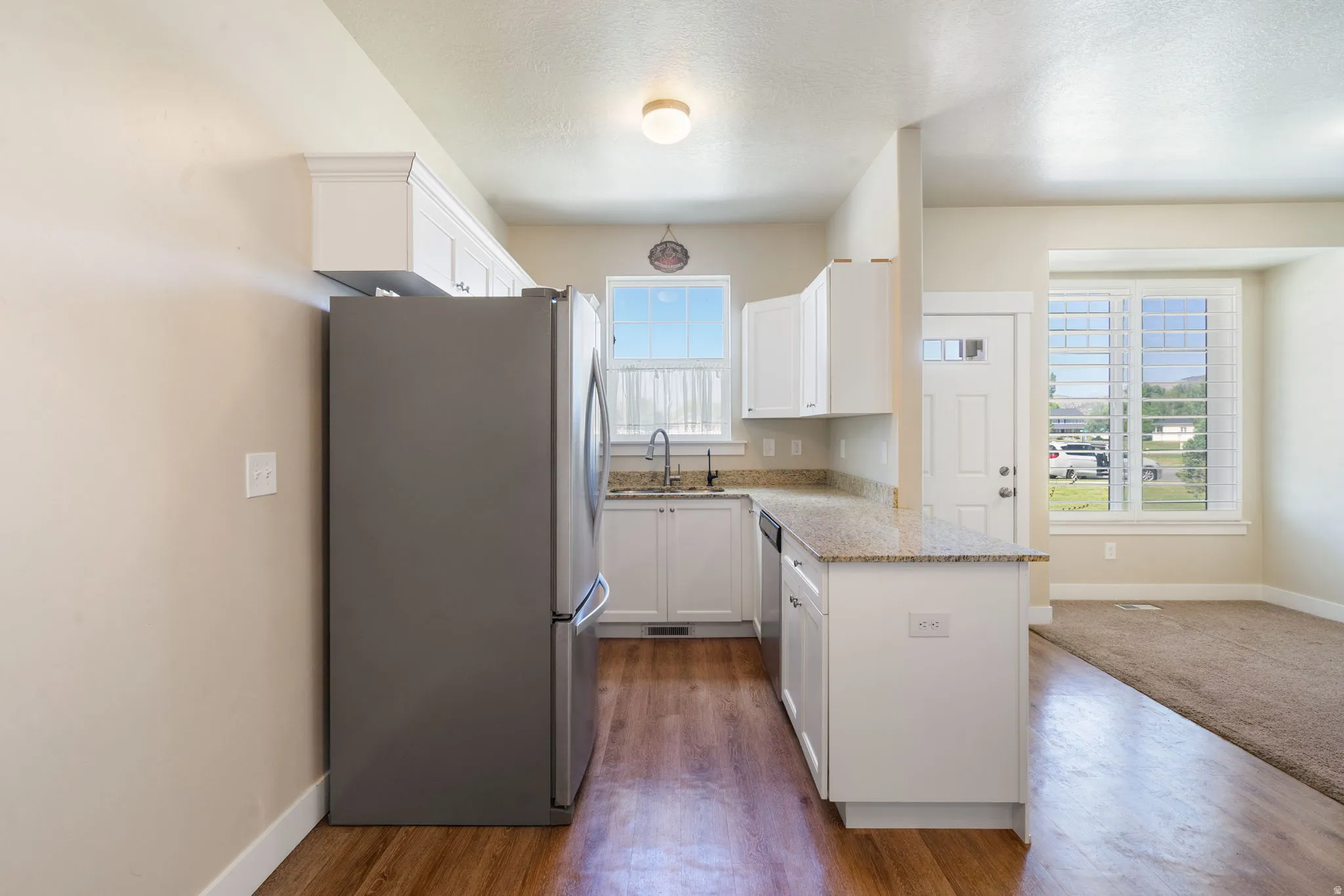Kitchen featuring white cabinetry, granite countertops, and wood-finish flooring