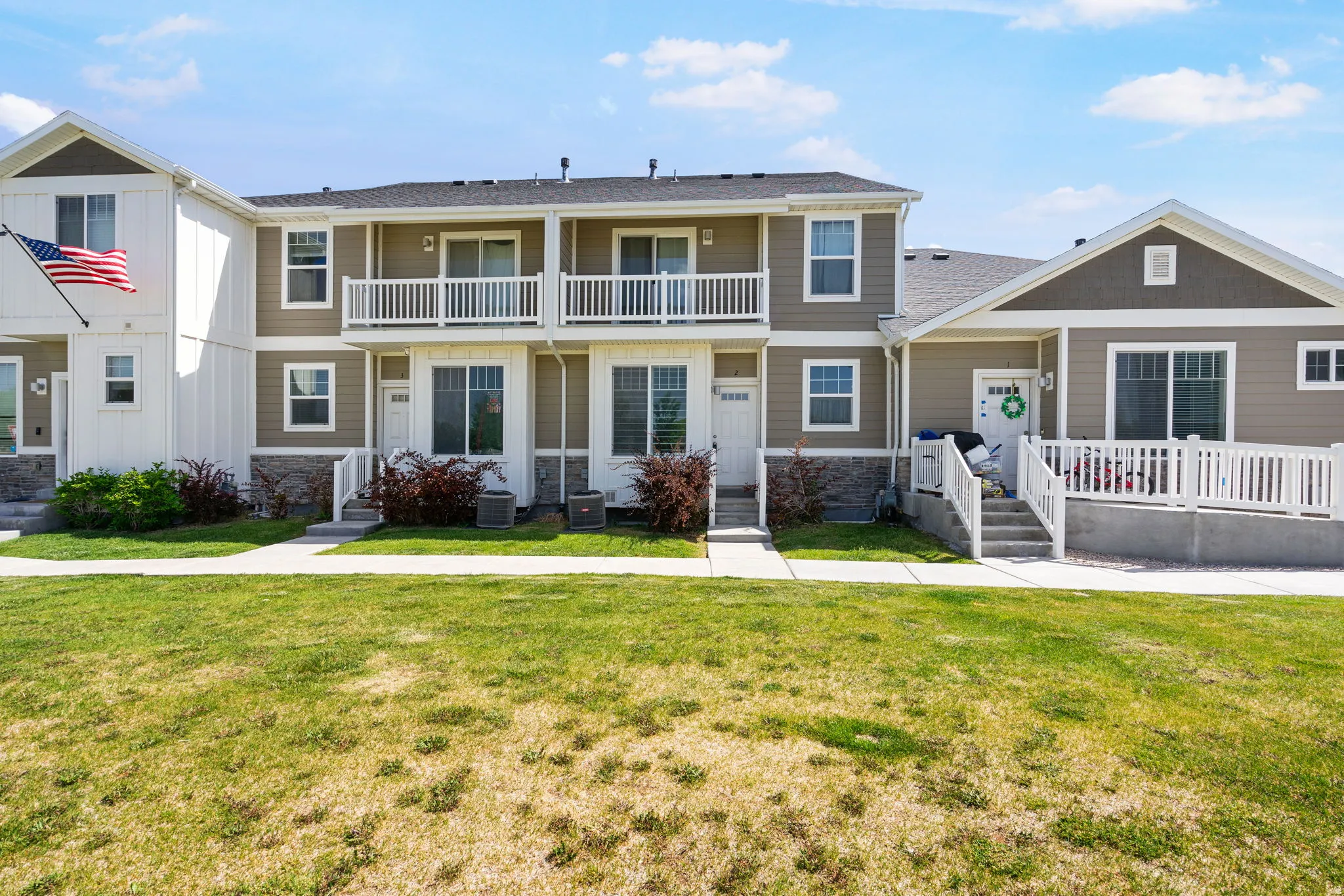 Townhome exterior featuring neutral siding, white trim, and stone accents & balcony