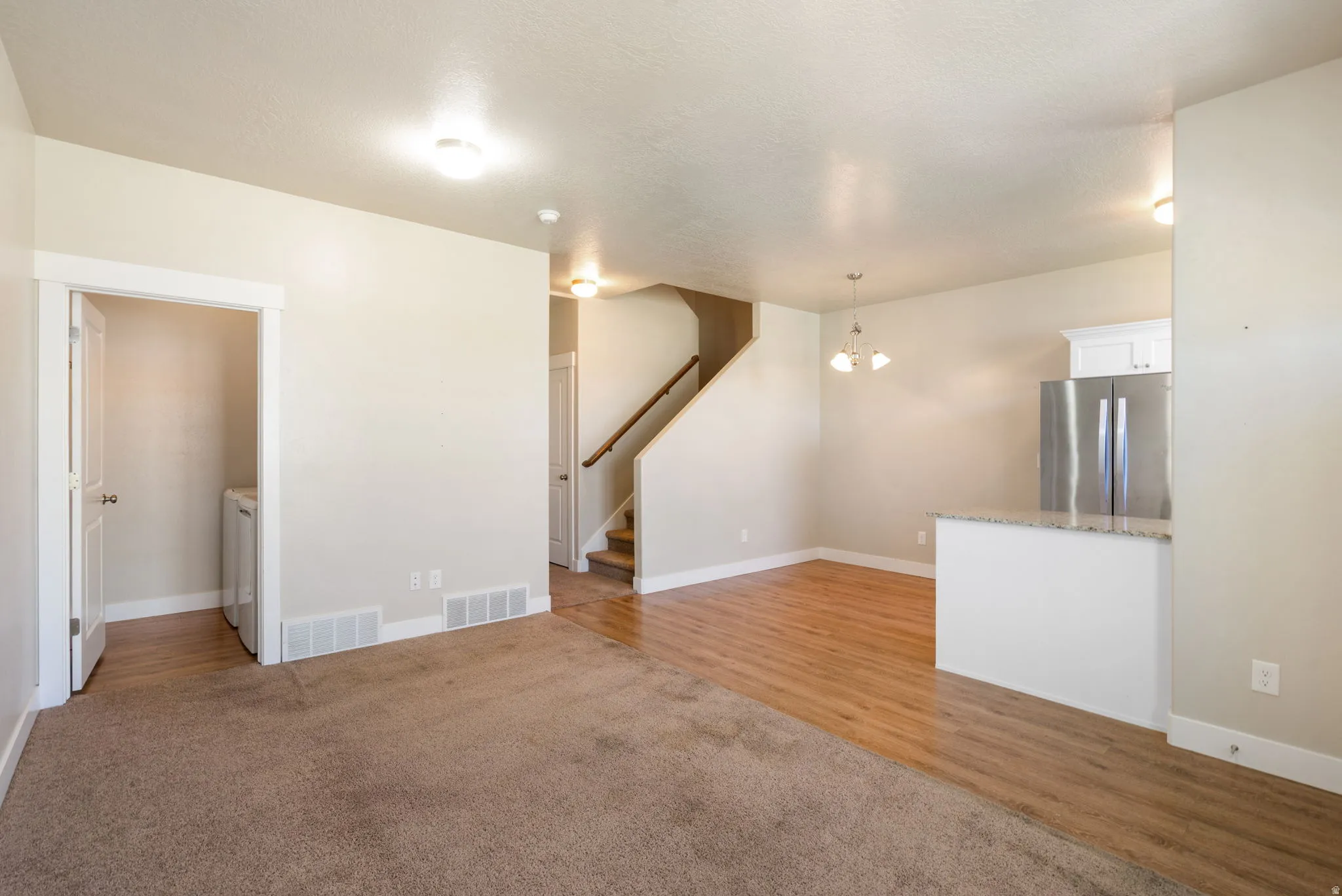 Bright open-concept living area featuring a mix of carpet and wood-finish flooring