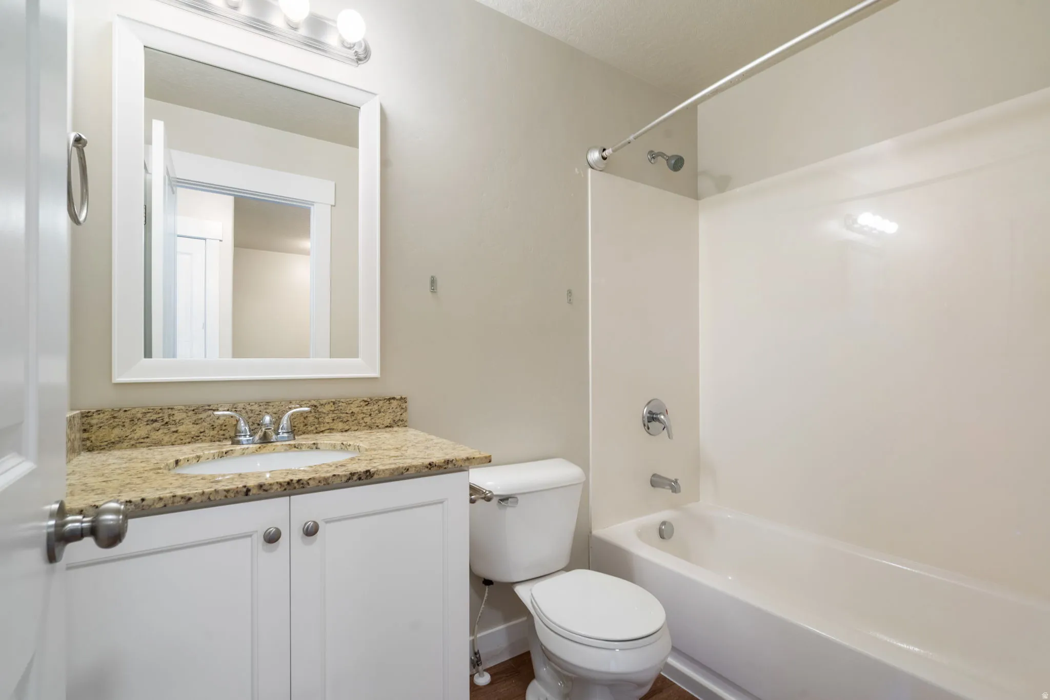 Bathroom featuring a white vanity with a granite-adult height-countertop, sink, and tub shower combo.