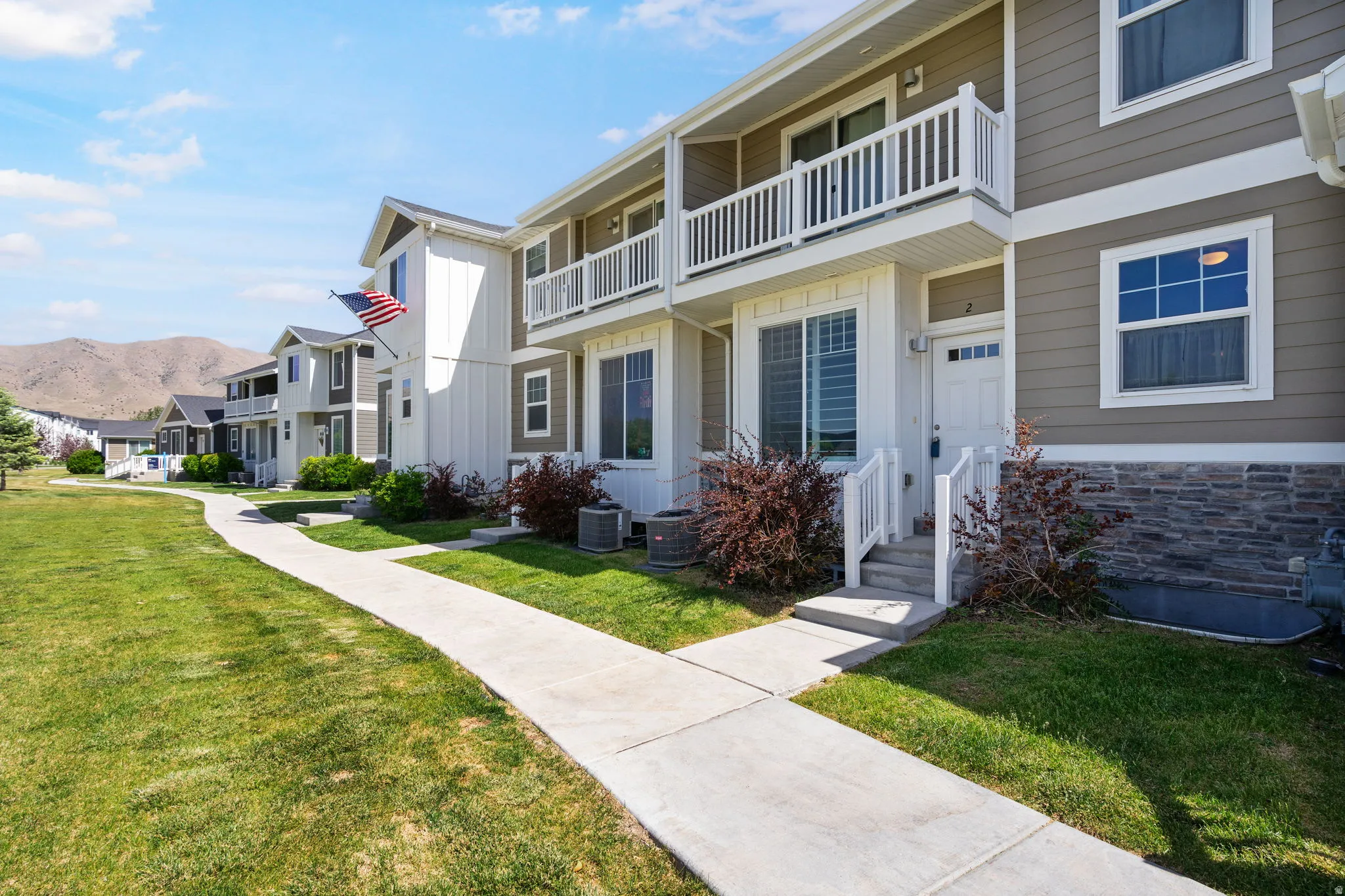 Townhome exterior featuring horizontal siding, balcony, vertical board and batten accents, and a stone facade foundation