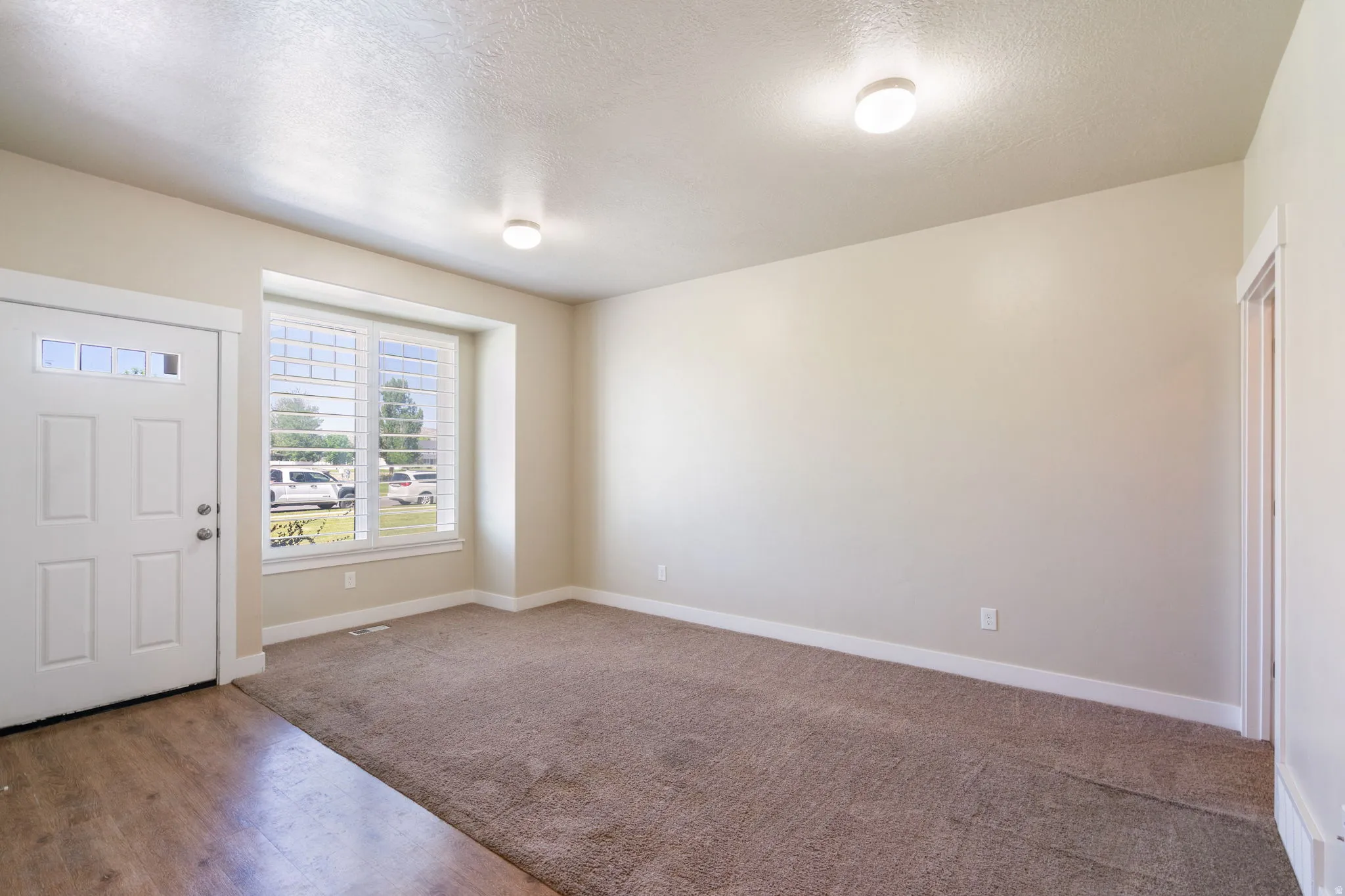 Entry area featuring a paneled door with decorative glass inserts, a large window with white shutters.