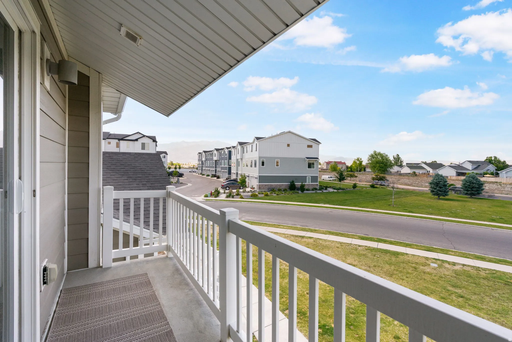 Exterior balcony featuring a concrete floor, white spindle railing, and a sliding glass door