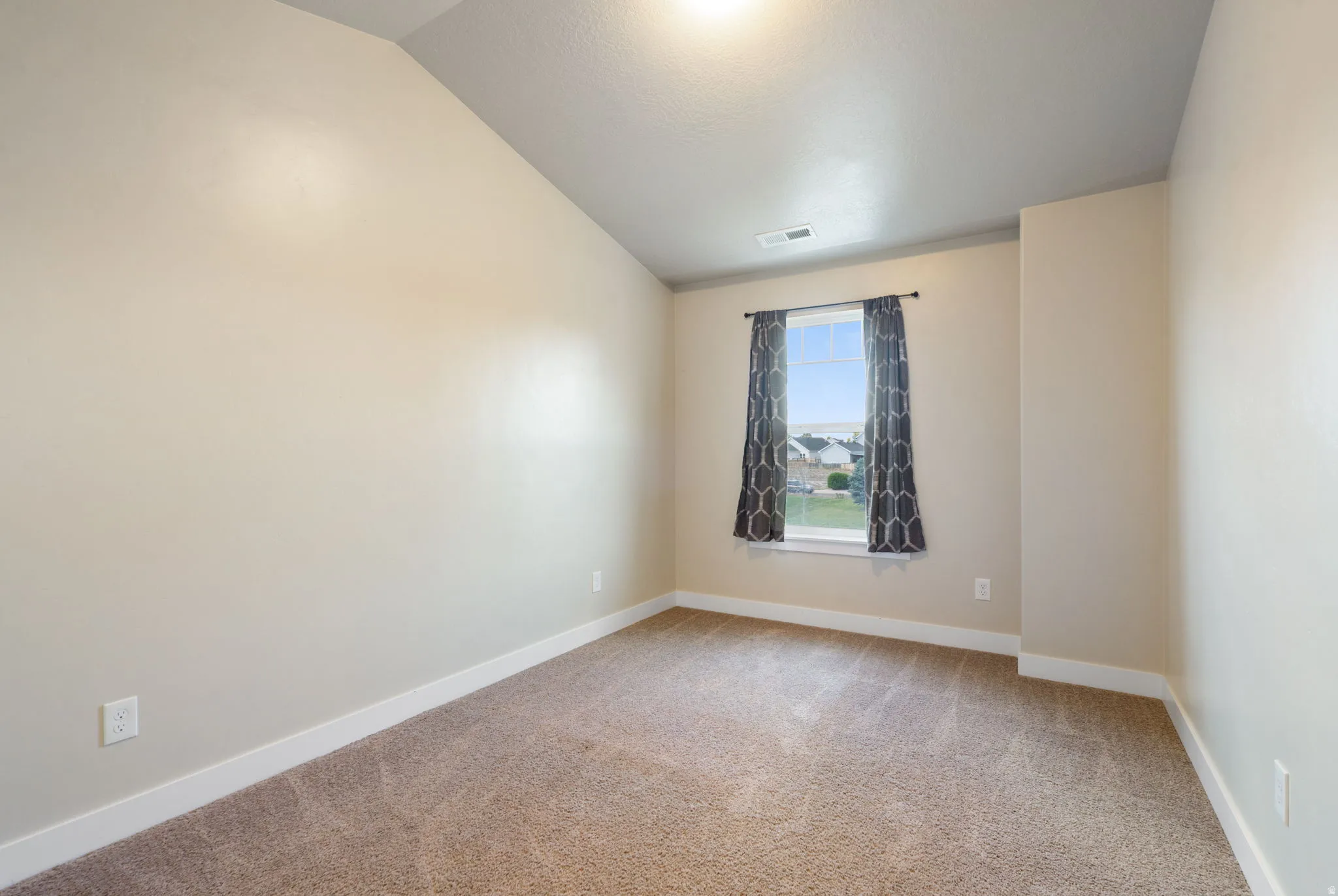 Neutral-toned carpeting paired with light-colored walls and white baseboards, in second bedroom.
