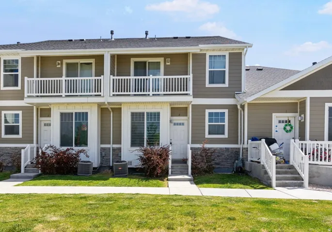 Multi-story townhome exterior featuring neutral siding, white trim, and a stone-look foundation