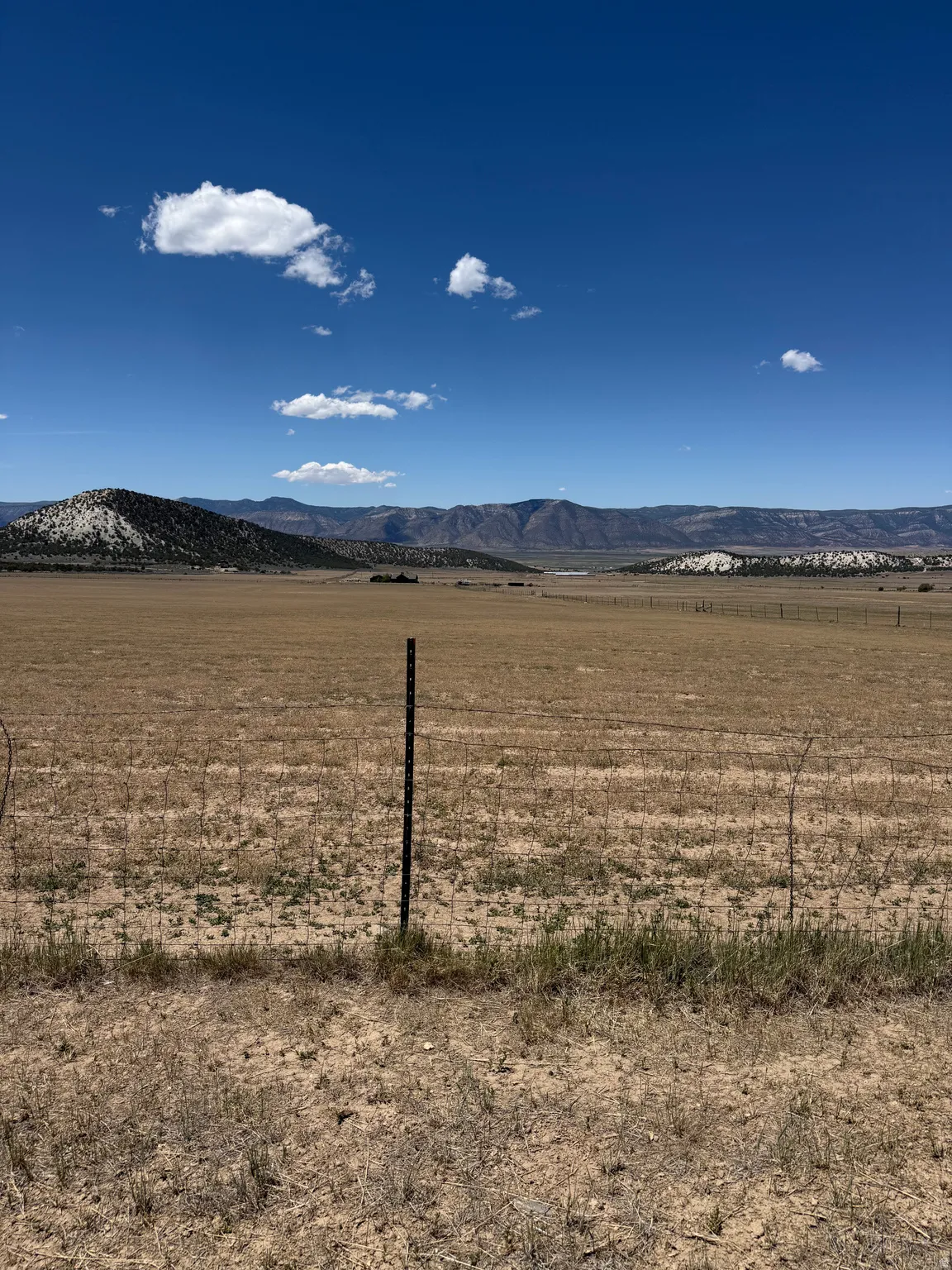 Expansive open field with distant mountain ranges and a clear sky