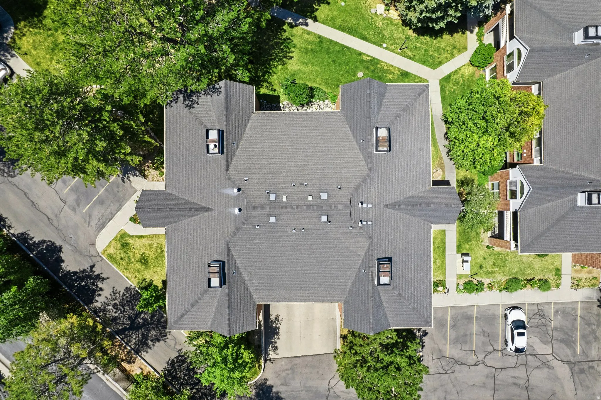 Overhead perspective of a multi-unit property featuring a dark-toned shingle roof with multiple skylights and vents