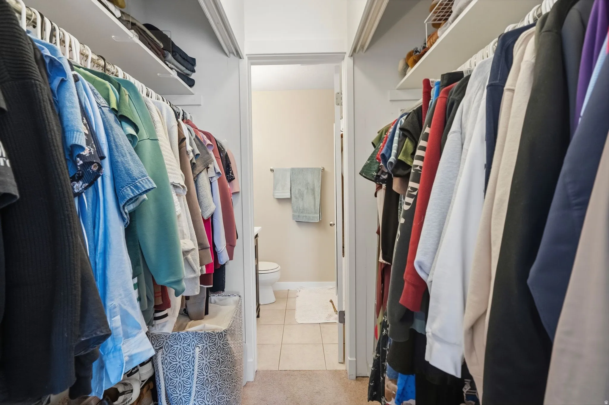 Walk-in closet featuring dual shelving and hanging rods located in primary bedroom