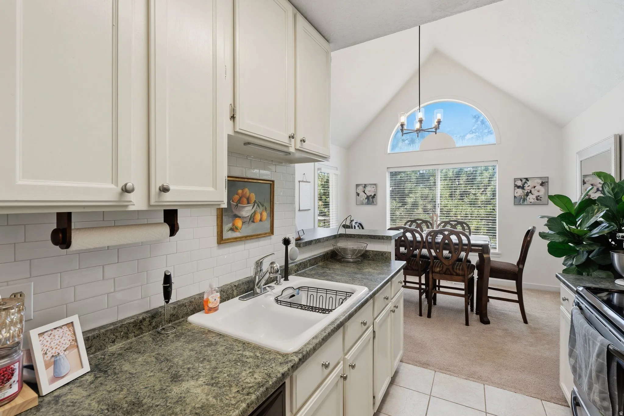 Kitchen featuring white cabinetry with silver-tone hardware, a white subway tile backsplash, and dark speckled countertops