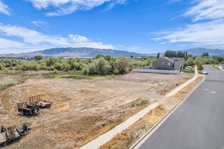 Expansive vacant lot featuring a cleared building envelope, paved street frontage, and a concrete sidewalk