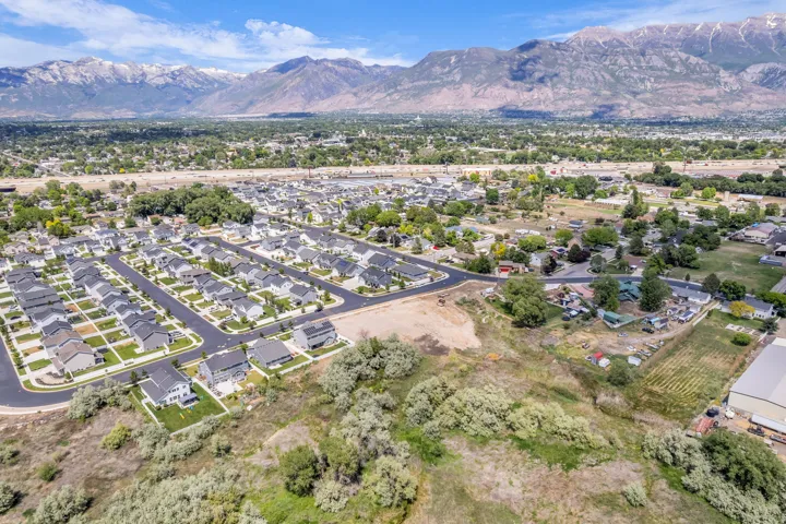 Expansive aerial showcasing a residential development with numerous single-family homes, complemented by a distant mountain range backdrop