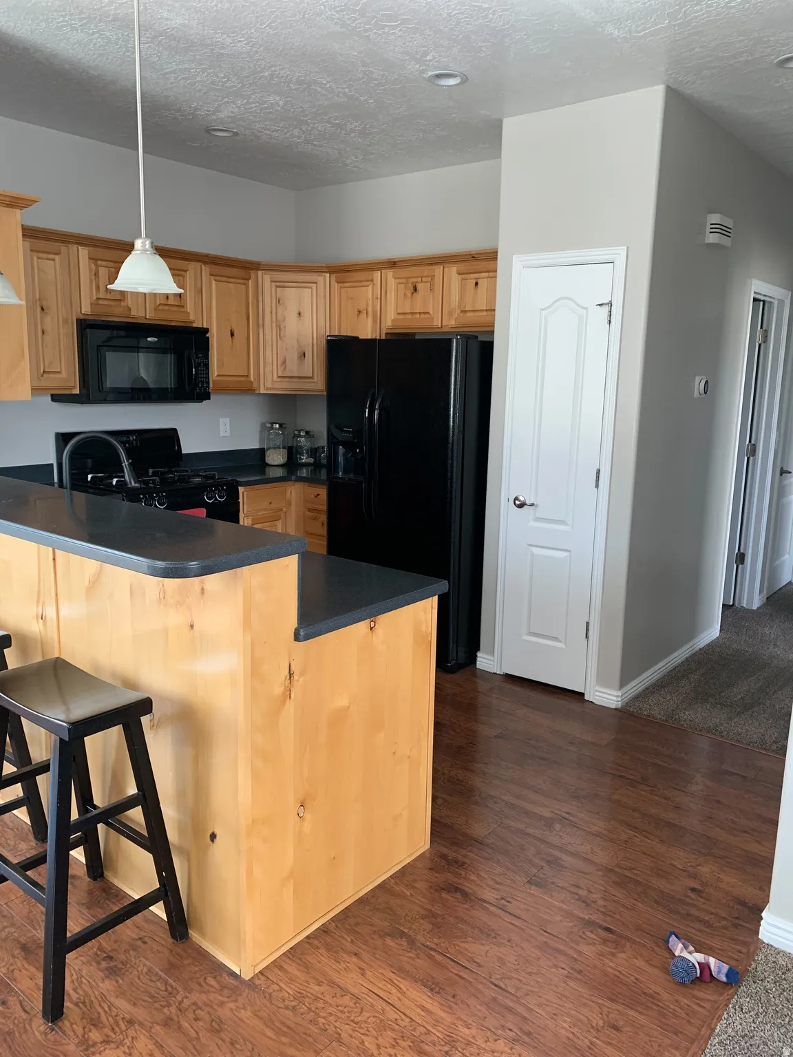 Kitchen featuring light wood cabinetry and dark countertops