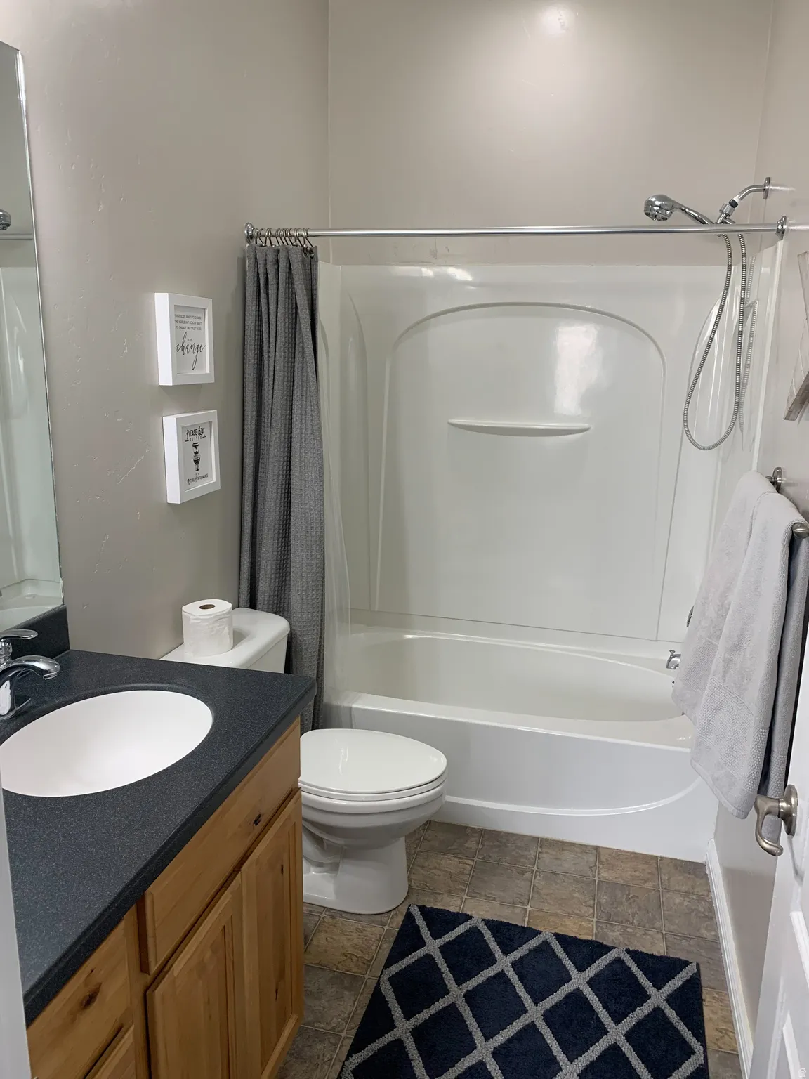 Bathroom featuring a white shower/tub combination, a toilet, and a vanity with a white sink
