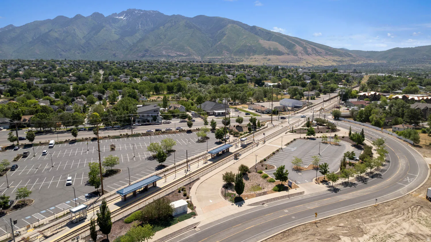 Aerial perspective showcasing a transportation hub with multiple parking lots and a light rail station