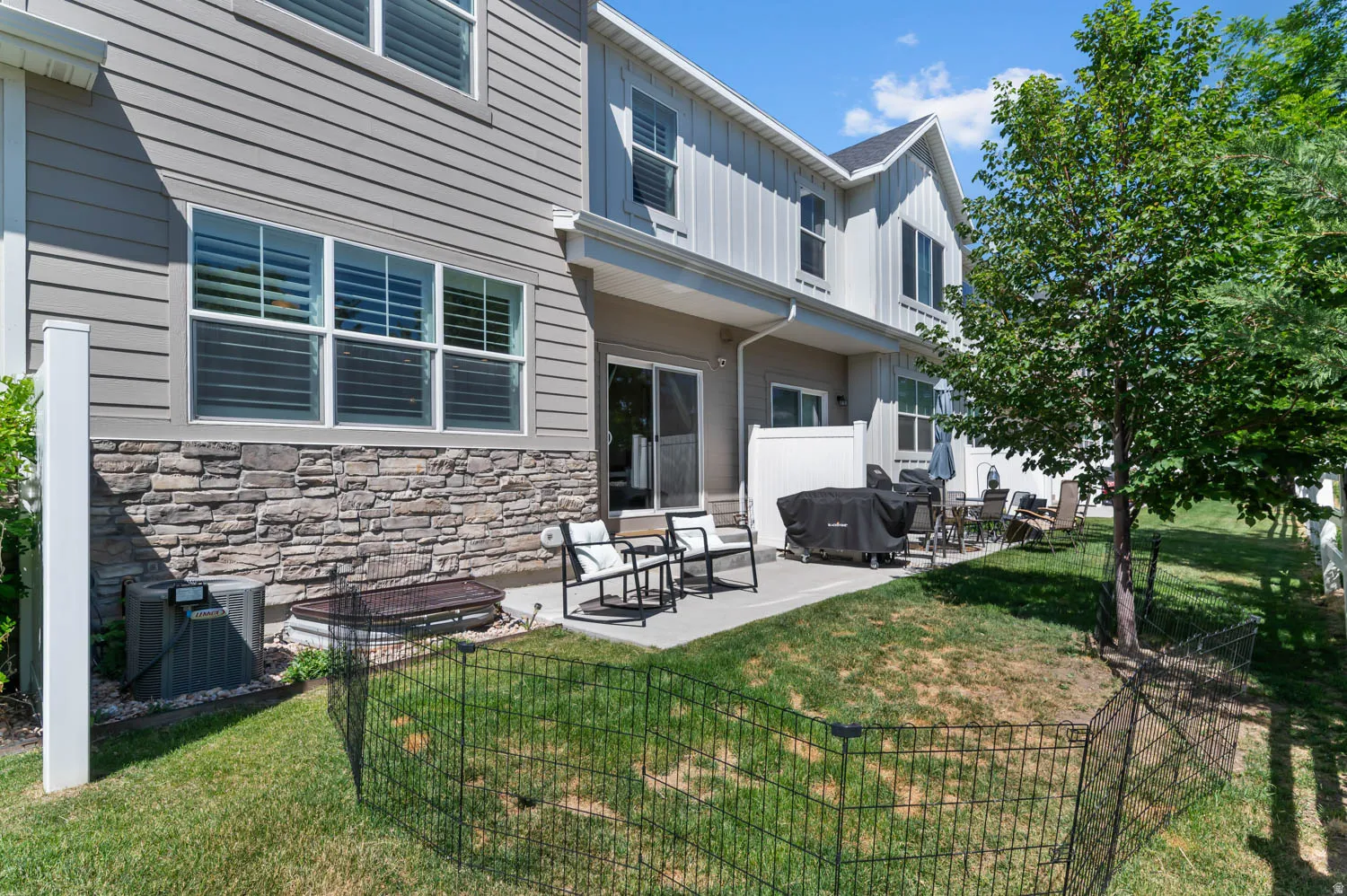 Expansive backyard featuring a concrete patio, mature tree, and partial privacy fencing