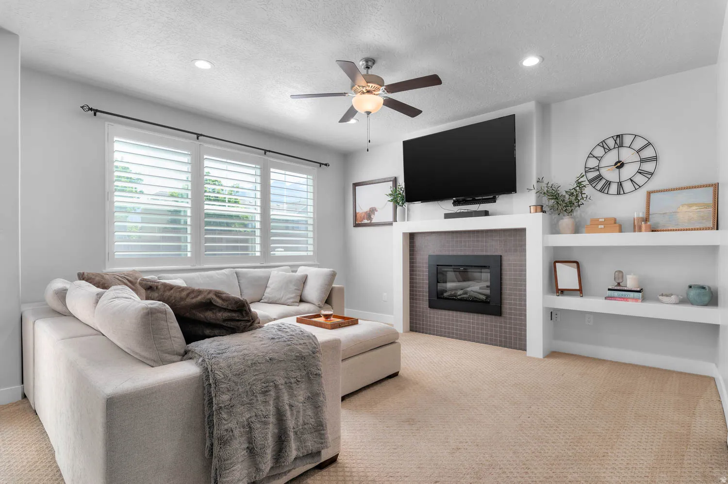 Integrated media center with an electric fireplace featuring a tiled surround and built-in shelving