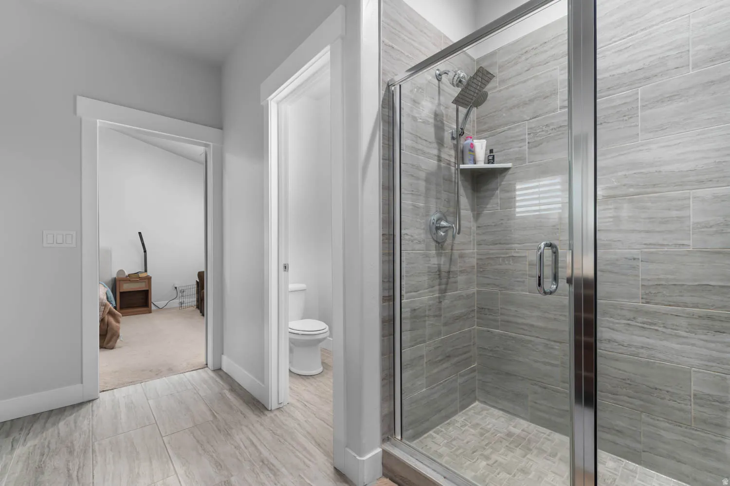 Glass-enclosed shower with horizontal-patterned tile surround and a chrome dual shower head fixture