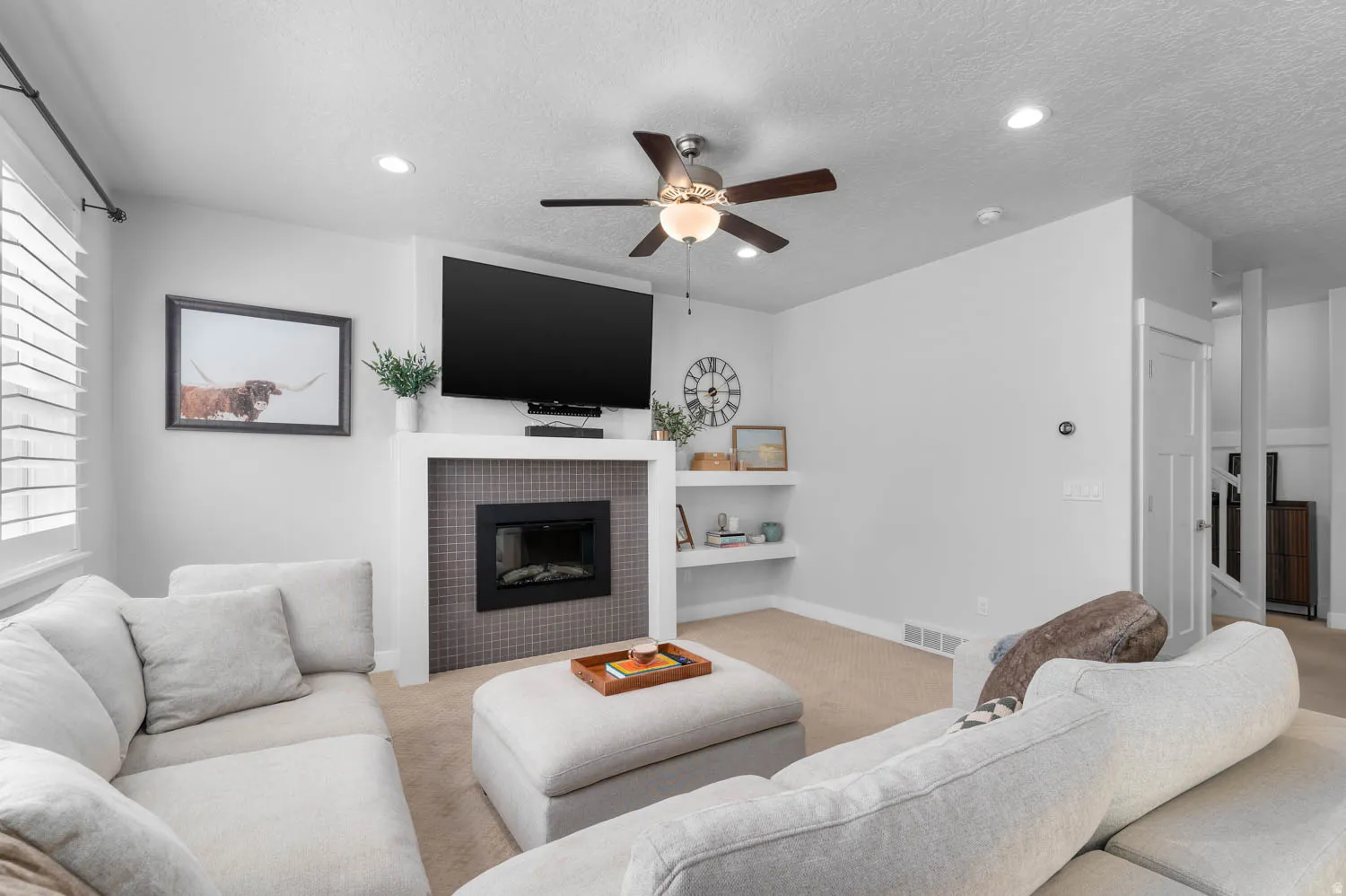 Living area featuring an electric fireplace with a tiled surround, recessed lighting, and a ceiling fan