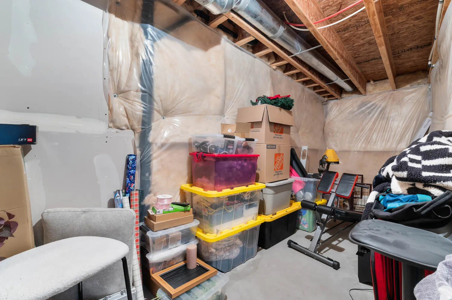 Unfinished basement space with exposed wooden joists and ductwork overhead