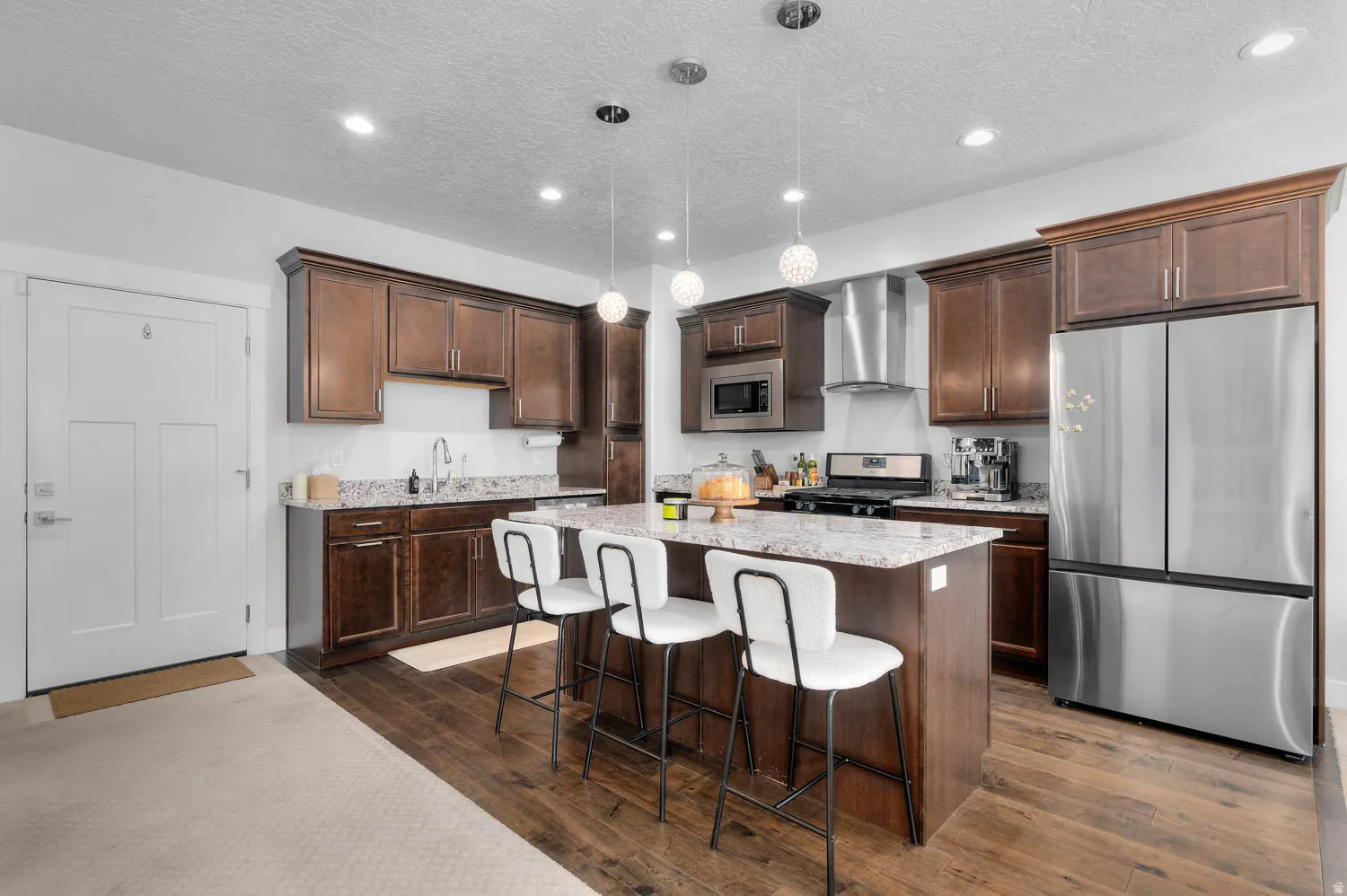 Kitchen featuring rich wood-finish cabinetry, stainless steel appliances, granite countertops, and wood-finish flooring