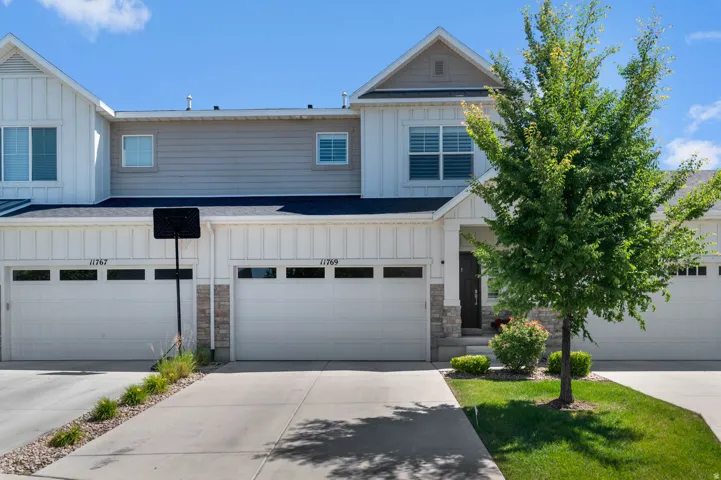 Modern townhome exterior featuring white board and batten siding, gray horizontal siding, and stone accents