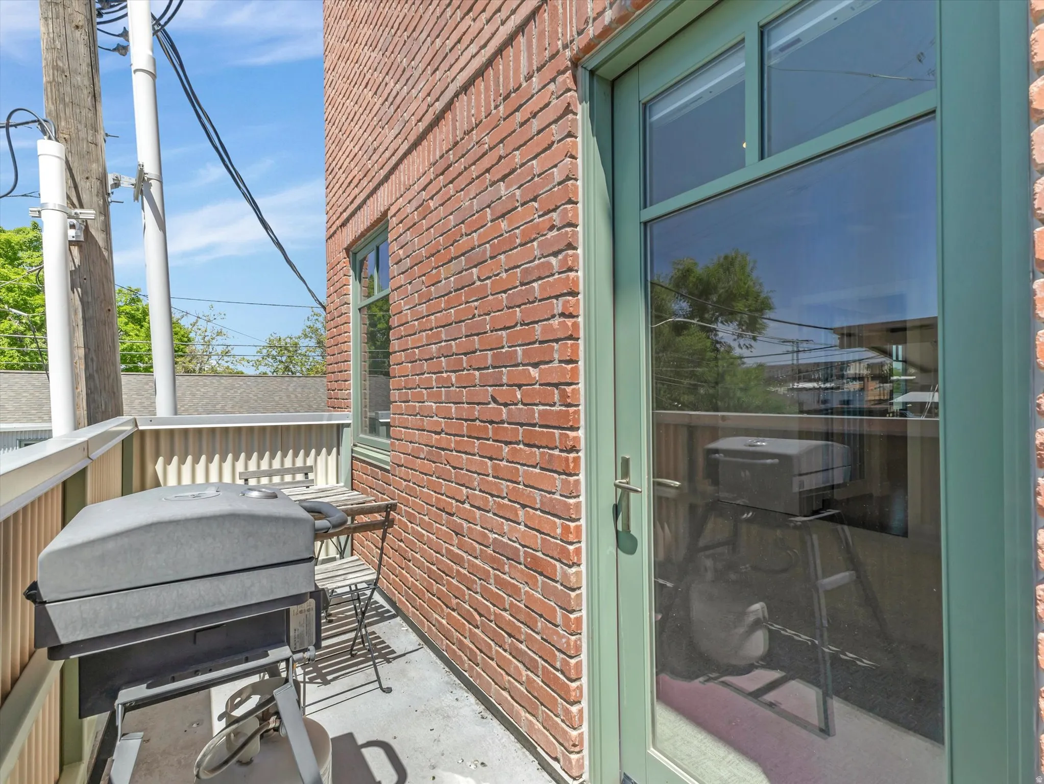Exterior balcony featuring a brick facade, green-framed glass door, and a concrete surface