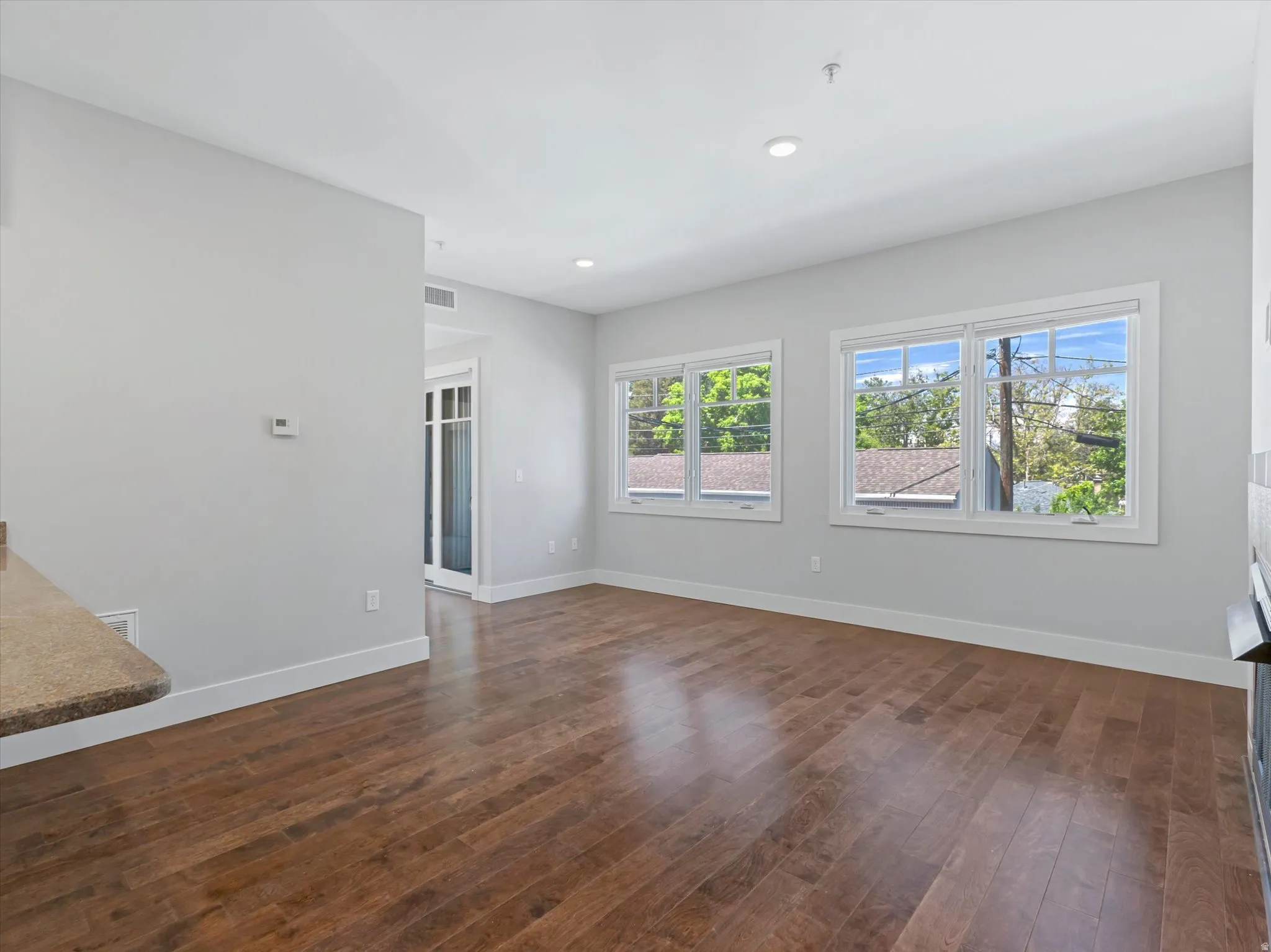 Spacious room featuring wood-finish flooring, light grey wall paint, and multiple windows with white trim